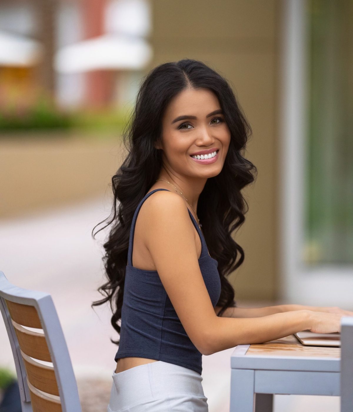 sharon wu writer sitting outside typing on laptop and smiling